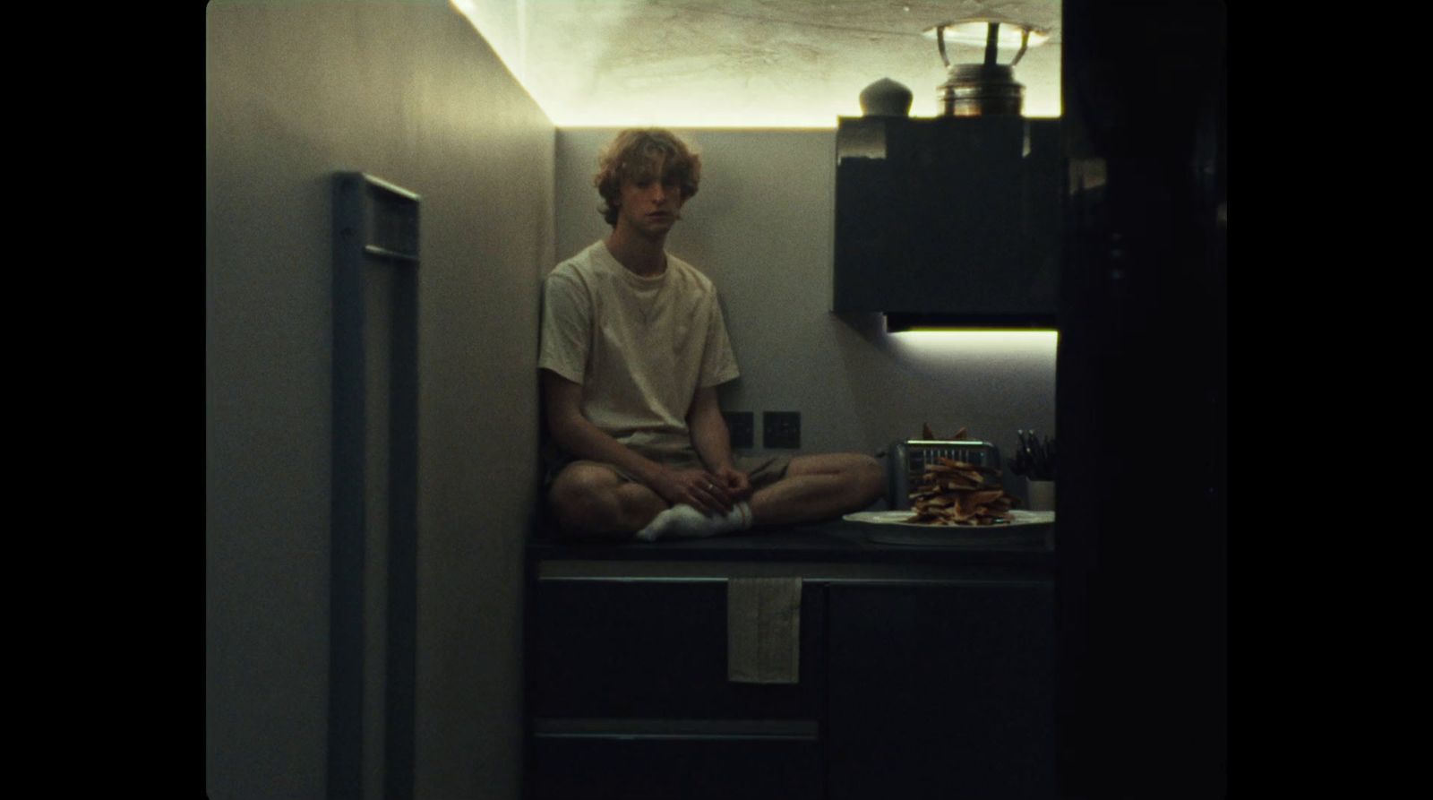 a man sitting on a counter in a kitchen