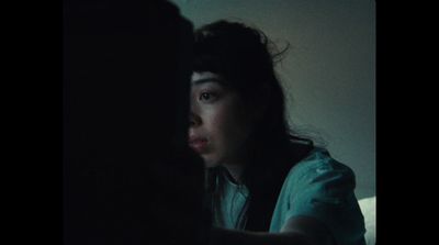 a woman sitting in a dark room looking at something