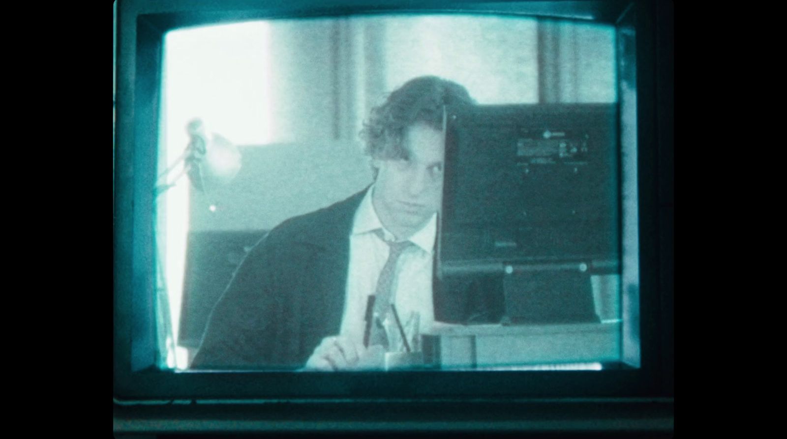 a man in a suit and tie is looking at a television screen