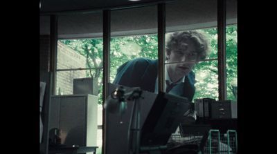 a man sitting at a desk with a suitcase in front of him