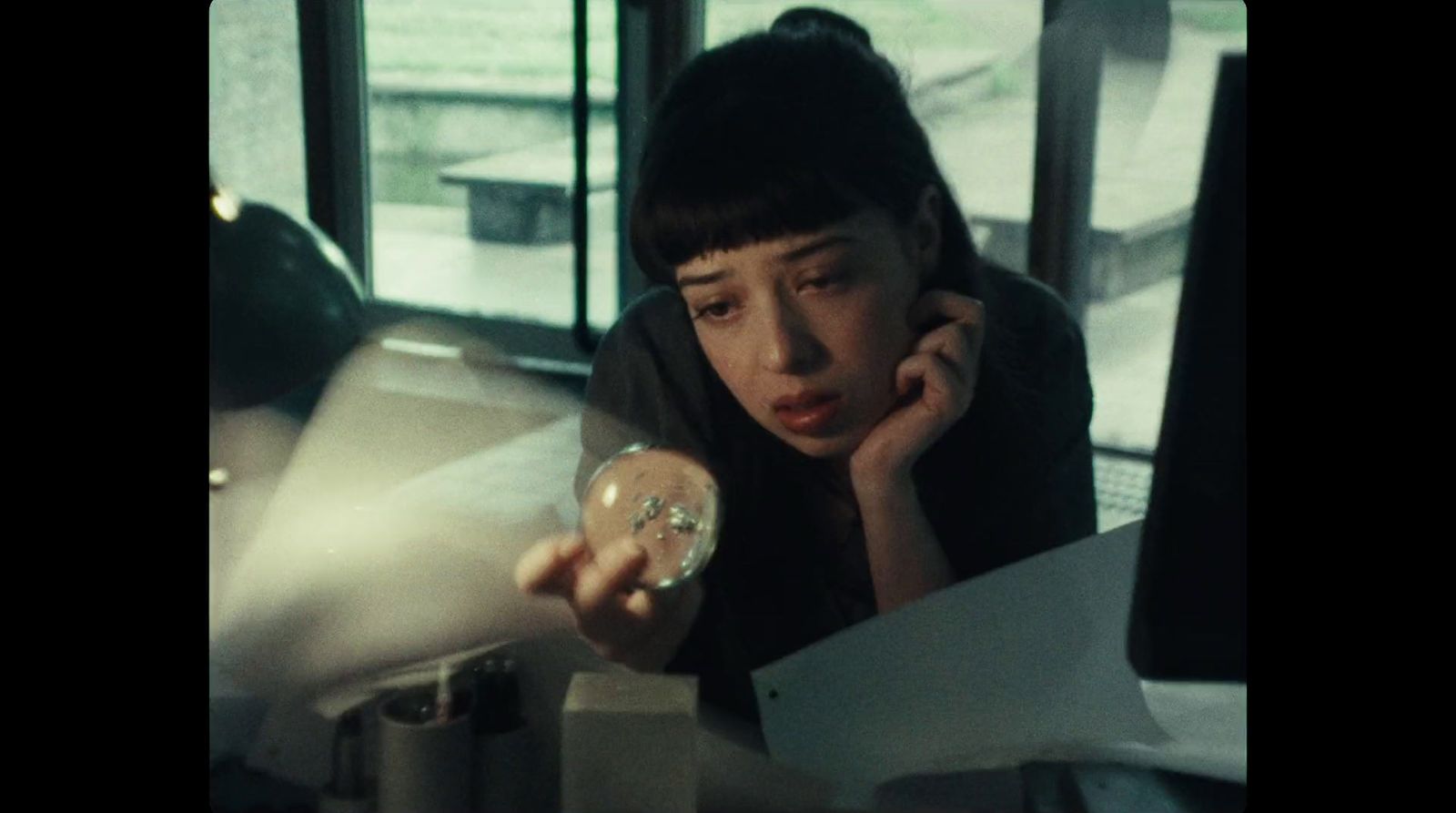 a woman holding a donut while sitting at a desk