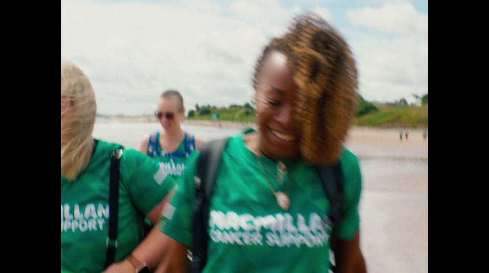 two women in green shirts walking on the beach