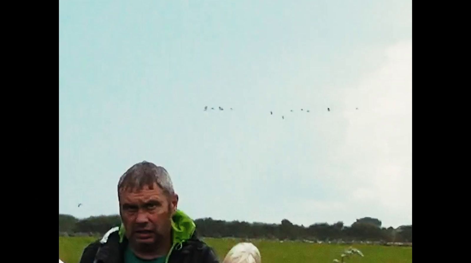 a man standing in a field with a kite in the sky
