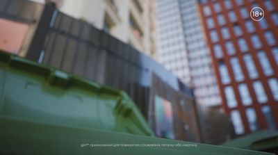 a green trash can sitting in front of a tall building