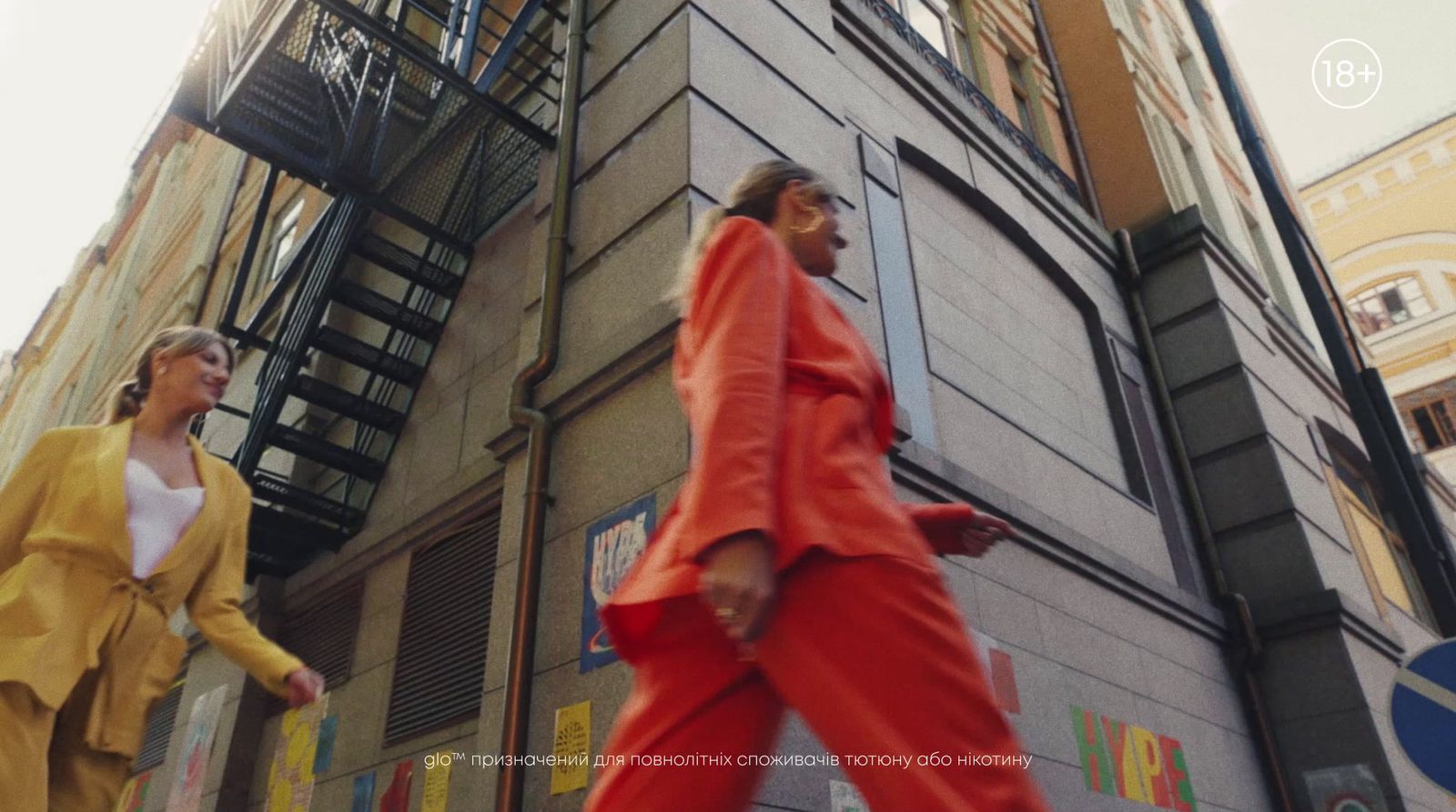 a couple of women walking down a street next to a tall building