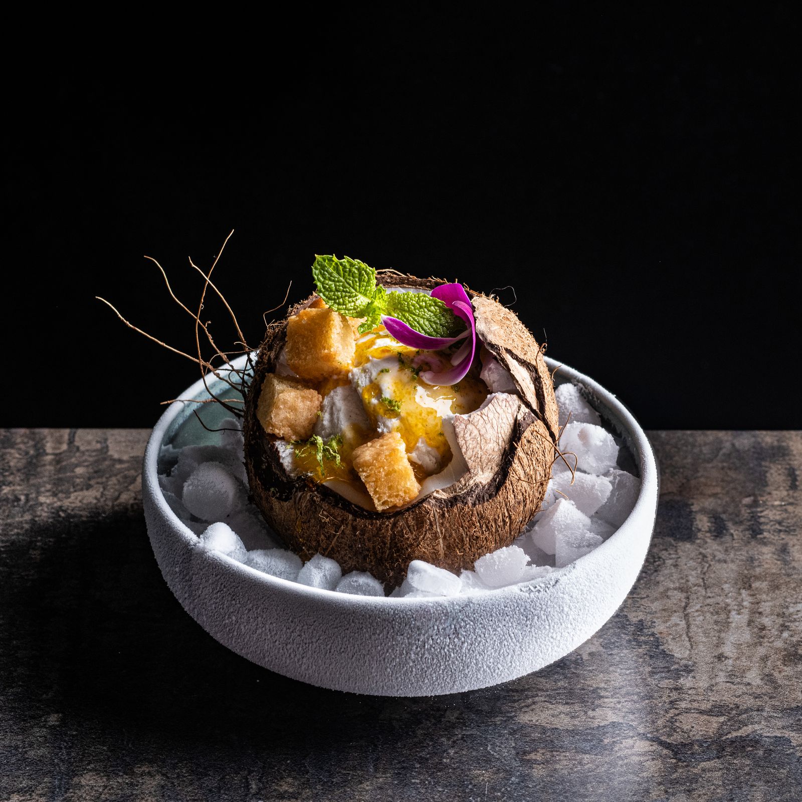 a bowl filled with ice and fruit on top of a table