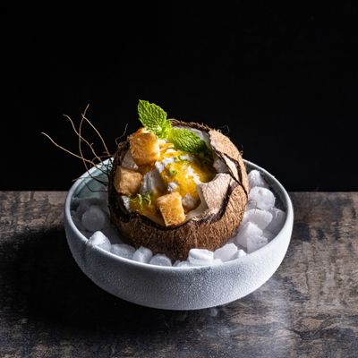 a bowl filled with ice and fruit on top of a table
