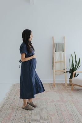 a woman in a blue dress standing on a rug