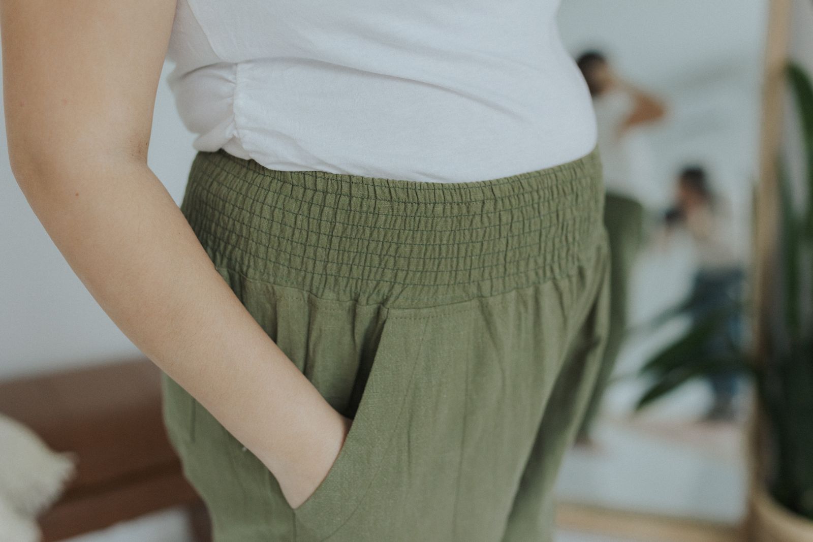 a woman wearing a white shirt and green pants