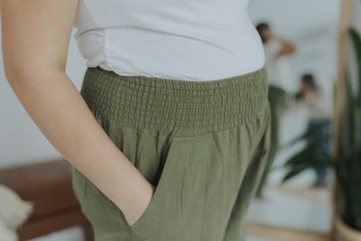 a woman wearing a white shirt and green pants