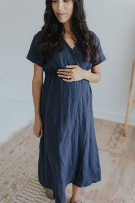 a pregnant woman in a blue dress standing on a rug