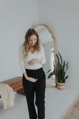 a pregnant woman in a white top and black pants