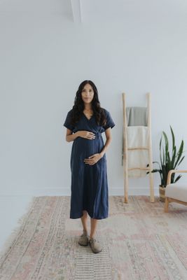 a pregnant woman standing on a rug in a white room