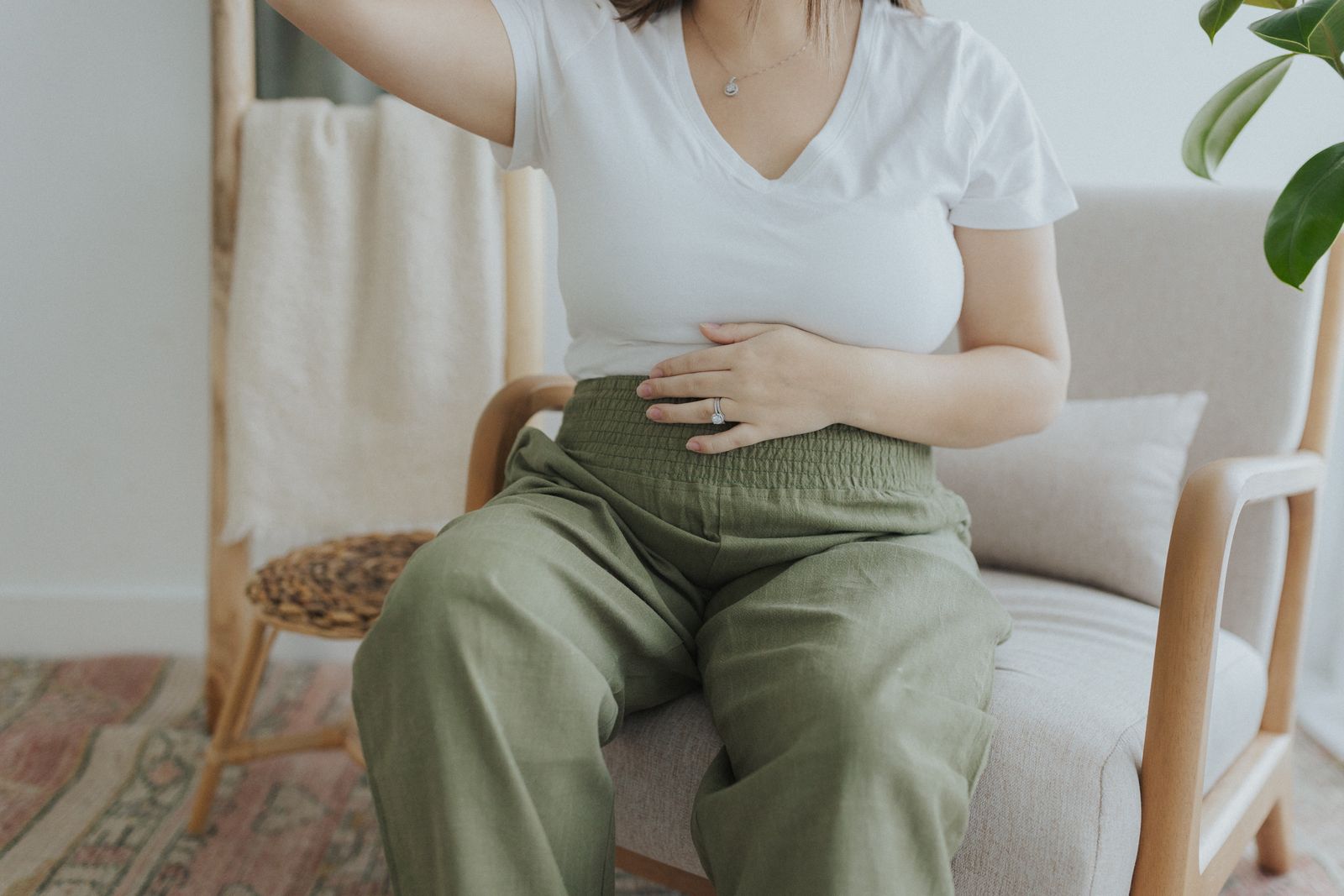 a woman sitting in a chair holding her stomach