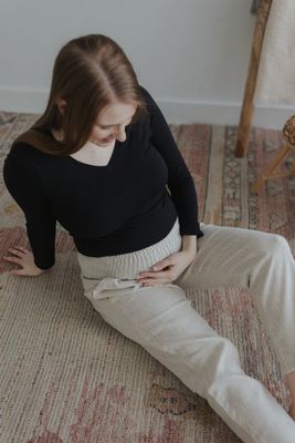 a woman sitting on the floor looking down at her stomach