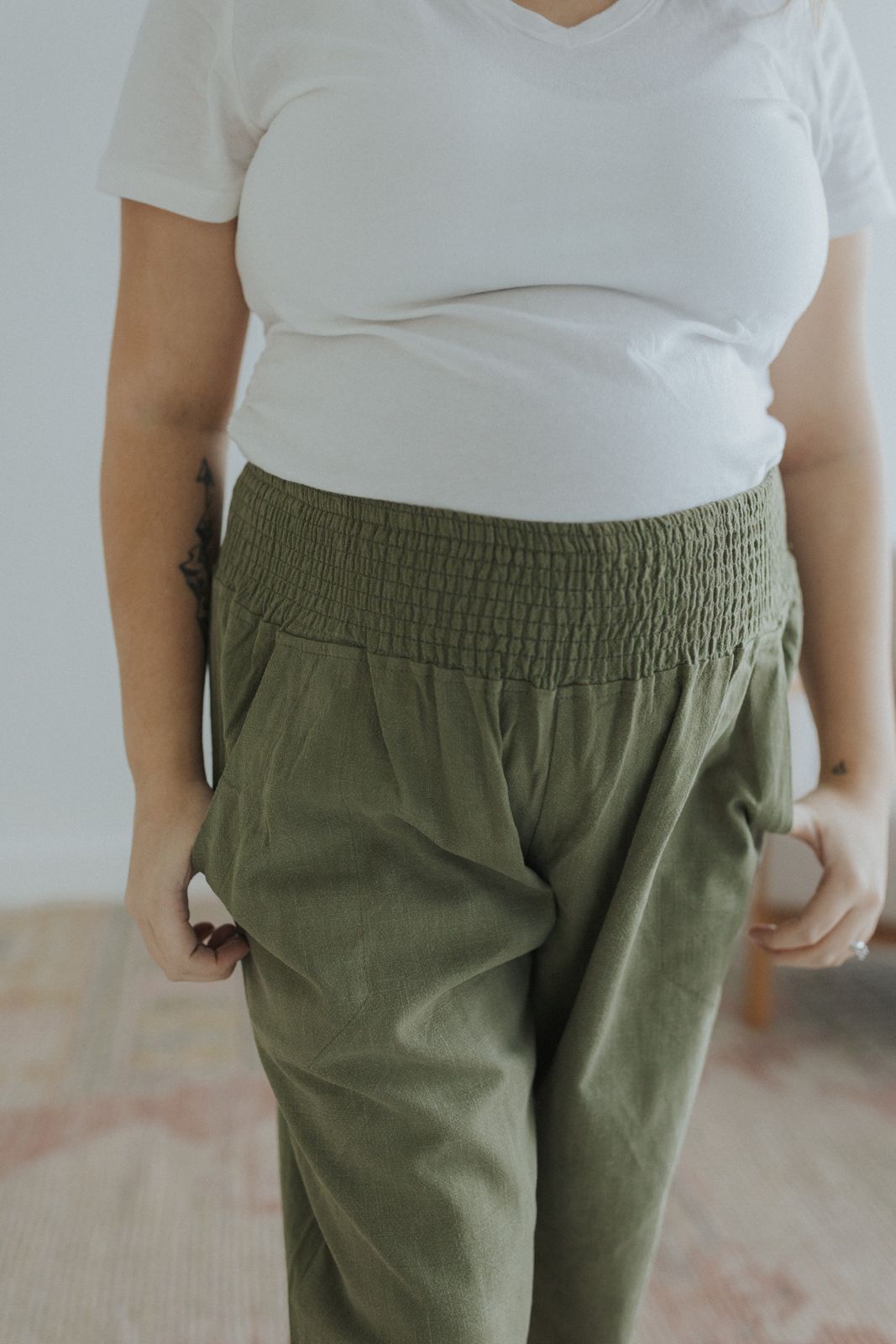 a woman wearing green pants and a white t - shirt