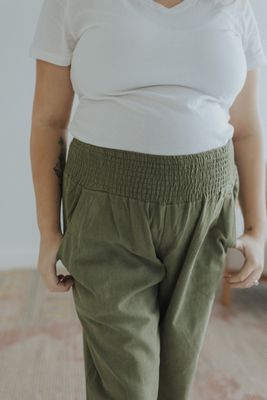 a woman wearing green pants and a white t - shirt