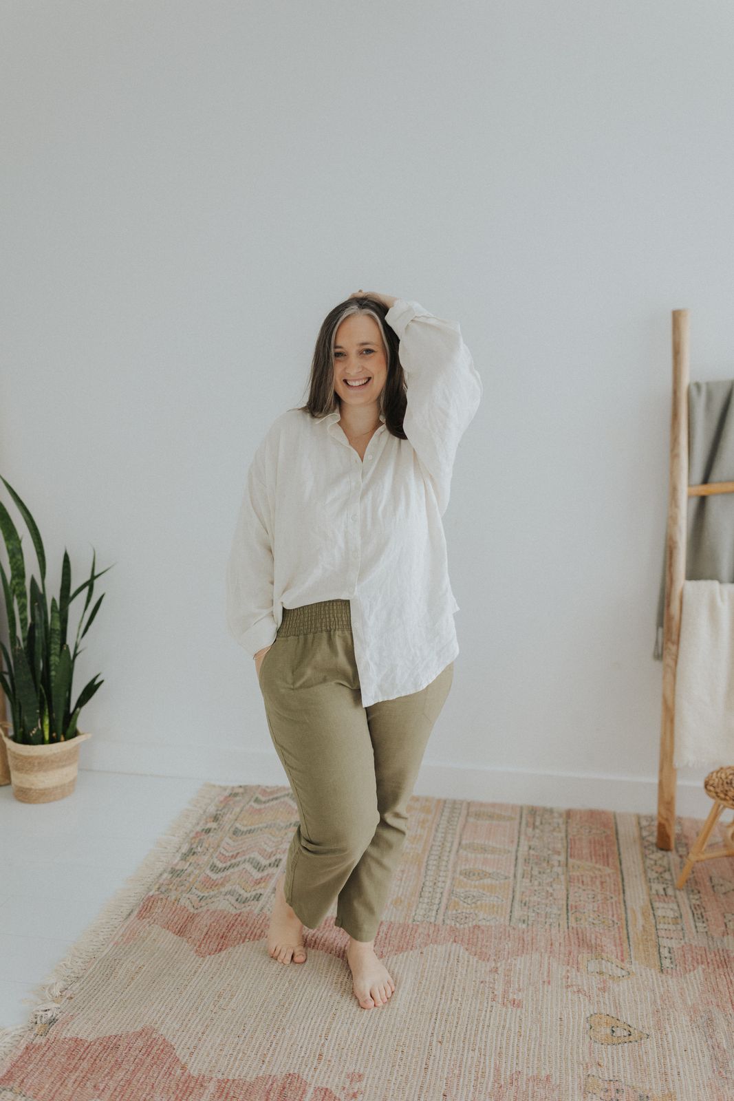 a woman standing on a rug with her hands behind her head