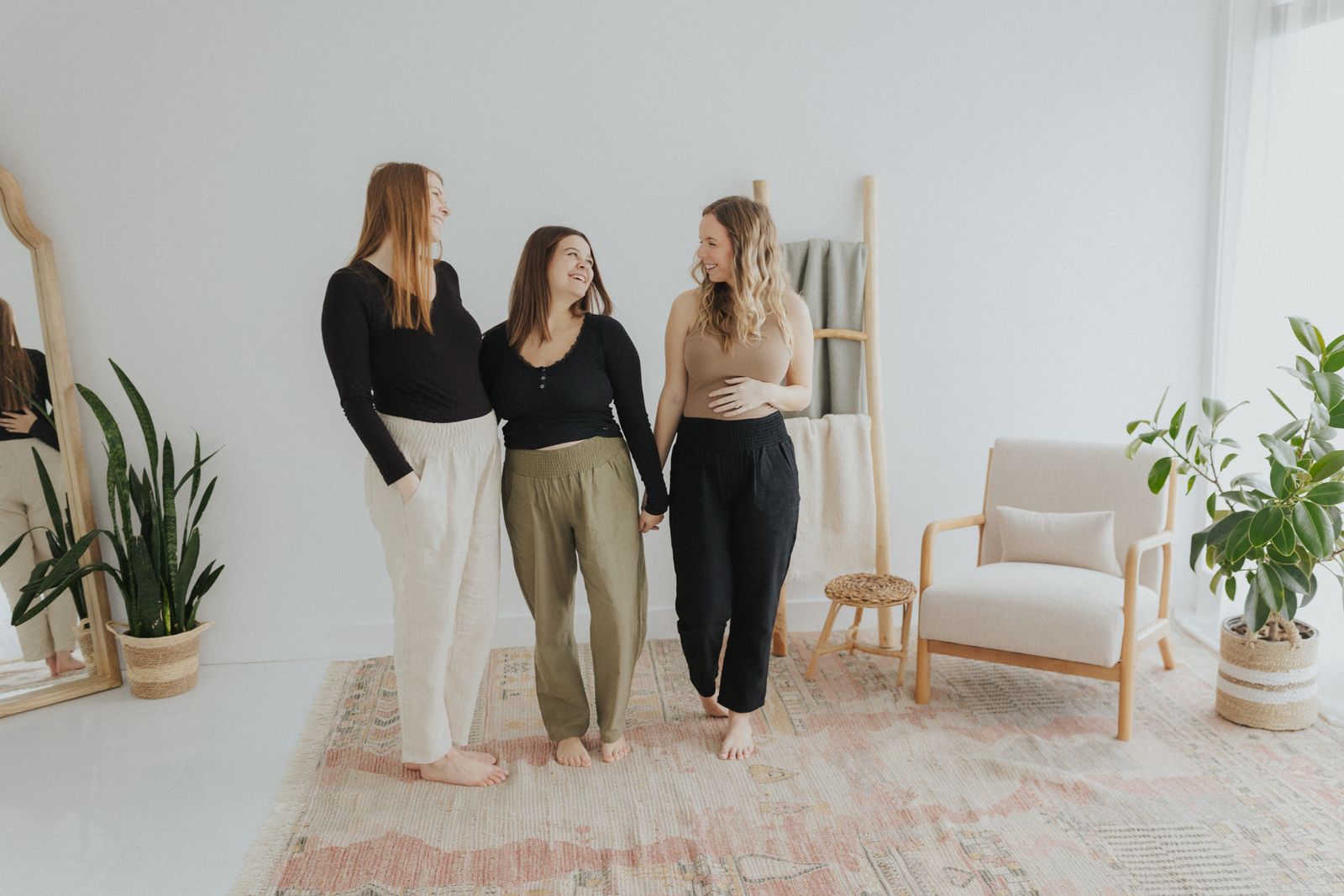 three women standing in a room with a rug on the floor