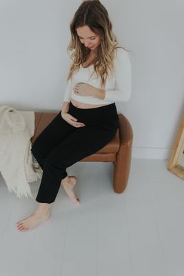 a pregnant woman sitting on a bench in a white room