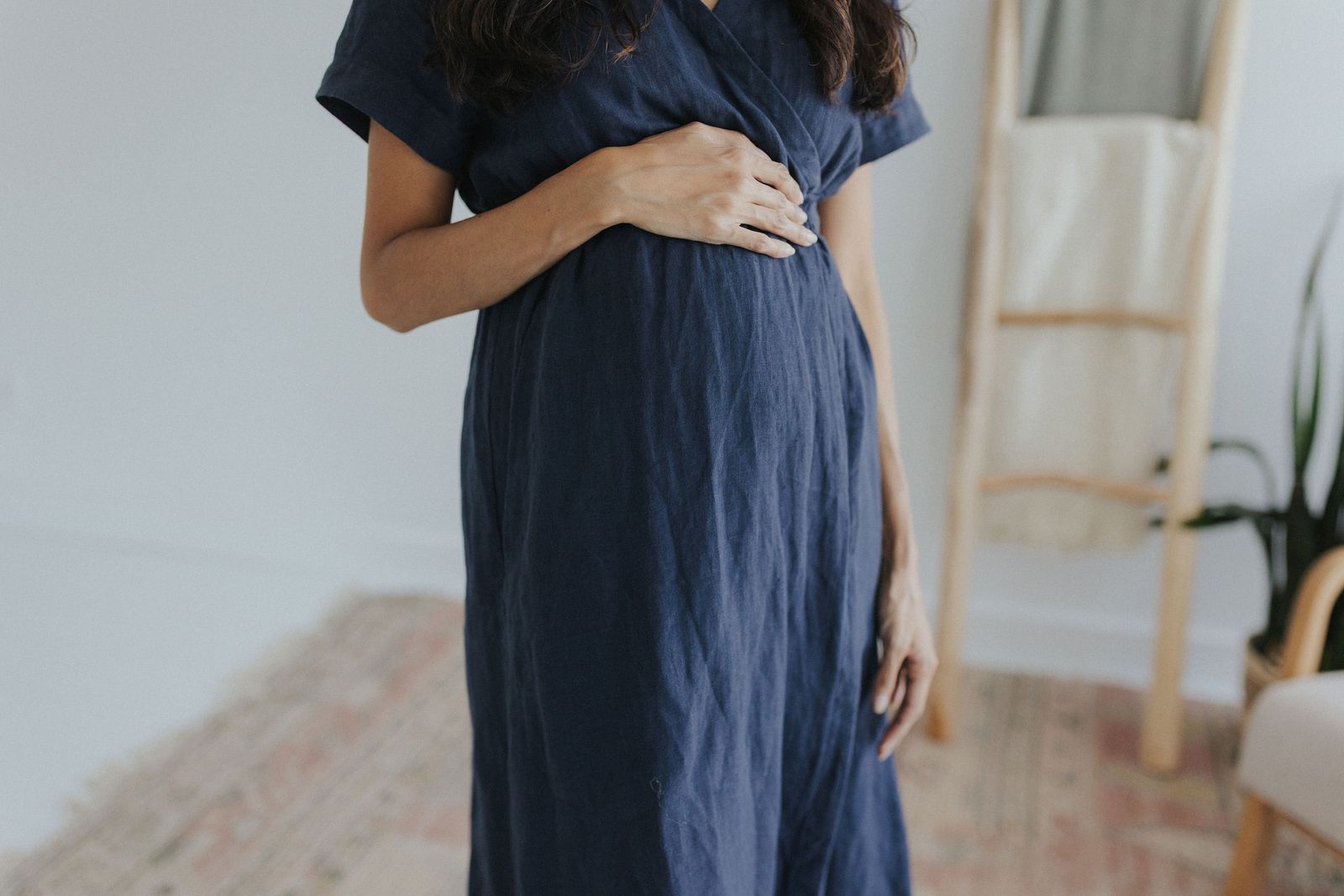 a pregnant woman in a blue dress standing in front of a mirror
