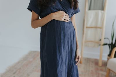 a pregnant woman in a blue dress standing in front of a mirror