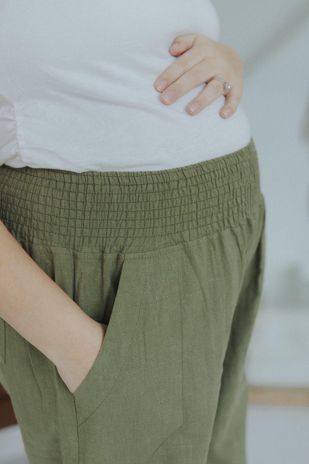 a pregnant woman wearing green pants and a white shirt