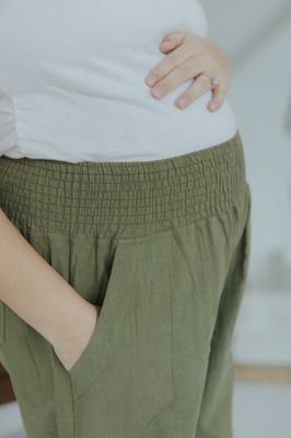 a pregnant woman wearing green pants and a white shirt