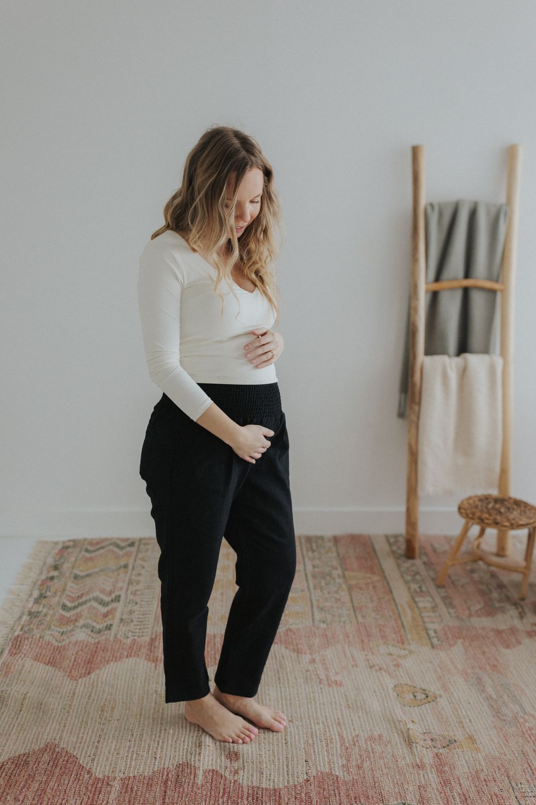 a pregnant woman in a white top and black pants