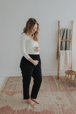 a pregnant woman in a white top and black pants