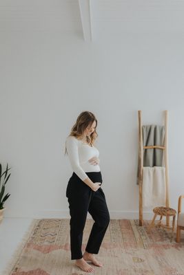 a pregnant woman standing on a rug in a white room