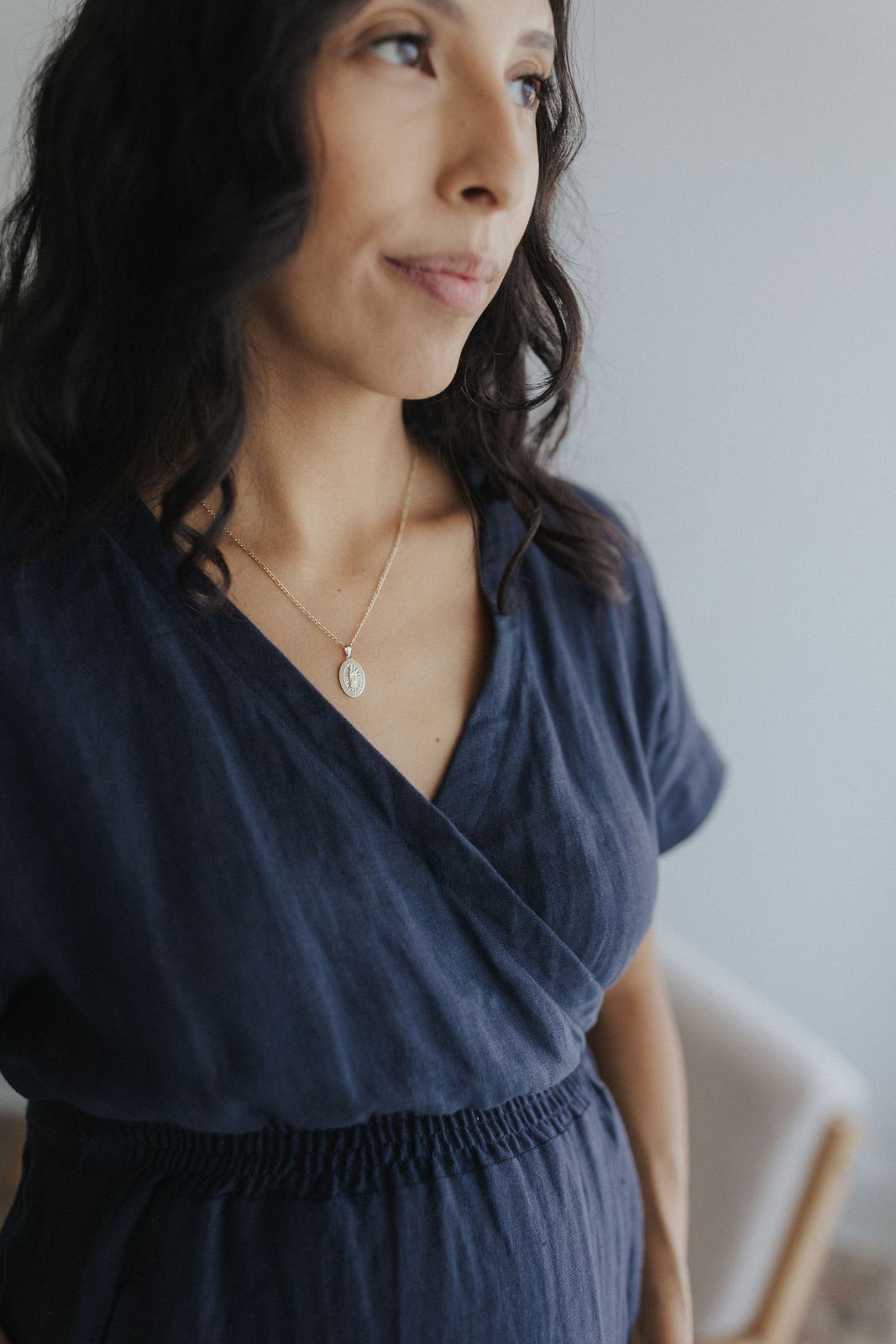 a woman wearing a blue dress and a gold necklace