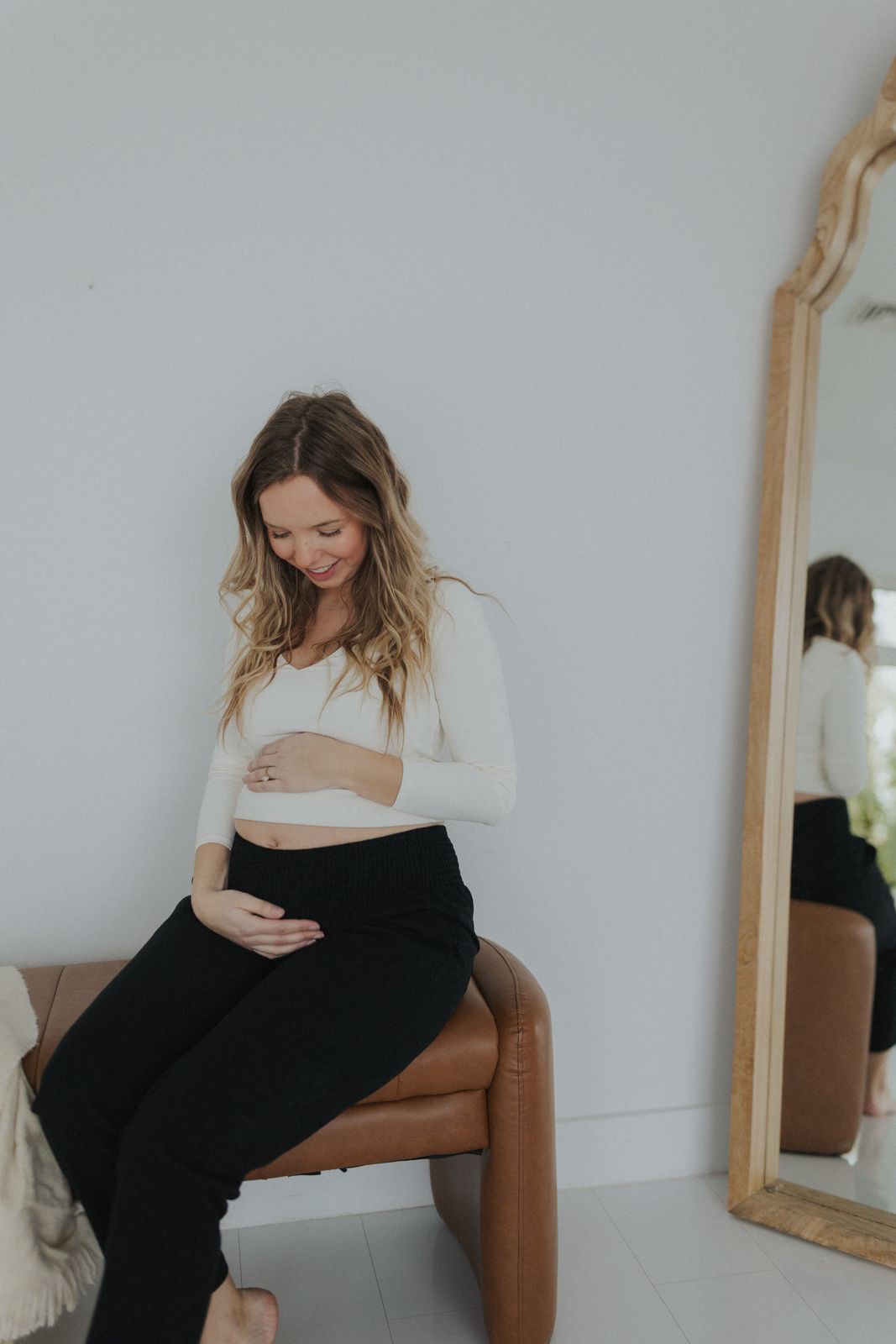 a pregnant woman sitting on a chair in front of a mirror