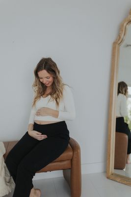 a pregnant woman sitting on a chair in front of a mirror