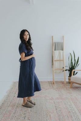 a pregnant woman standing on a rug in a white room