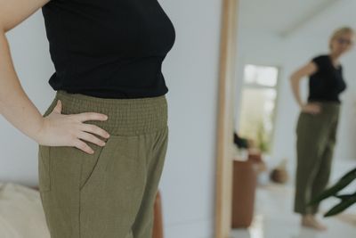 a woman standing in front of a mirror with her hands on her hips