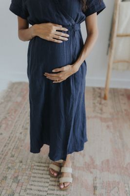 a pregnant woman in a blue dress poses for a picture
