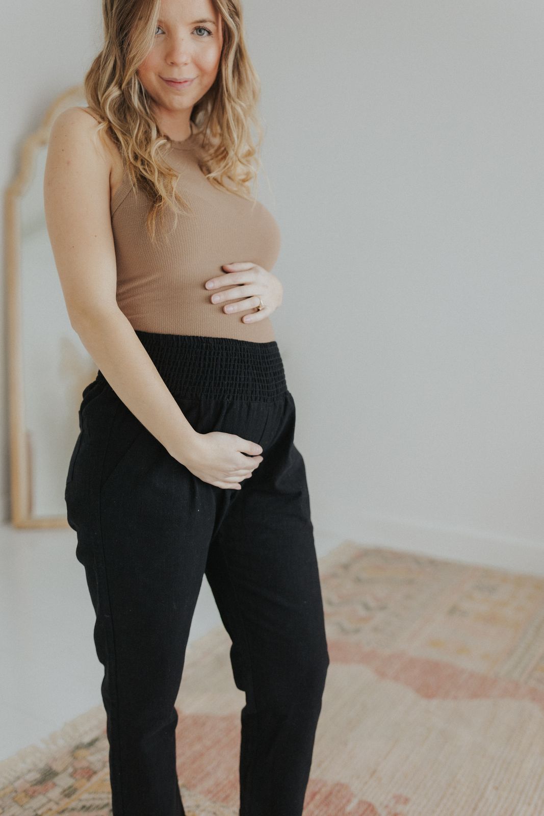 a pregnant woman in a tan top and black pants