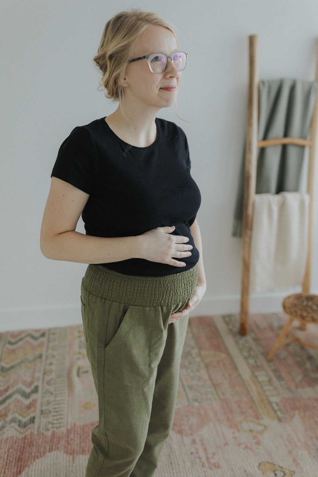 a woman standing in front of a wall wearing glasses