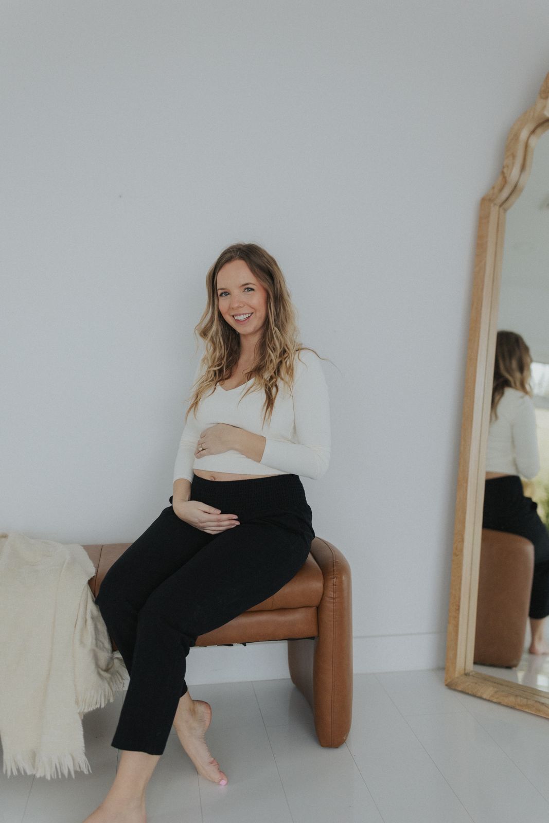 a pregnant woman sitting on a bench in front of a mirror