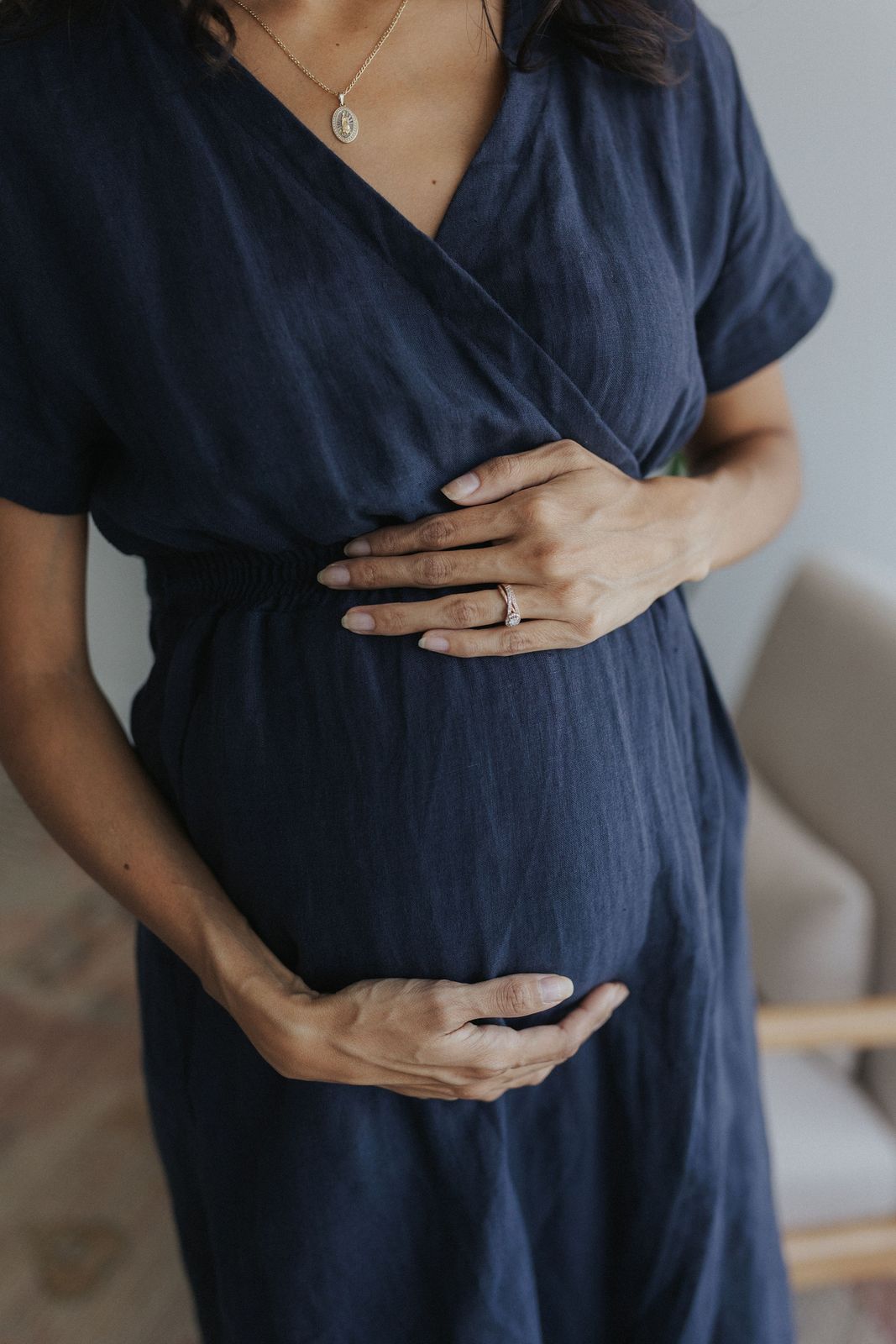 a pregnant woman in a blue dress holding her stomach