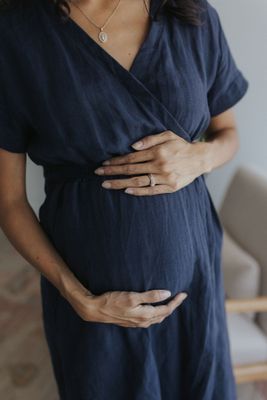 a pregnant woman in a blue dress holding her stomach