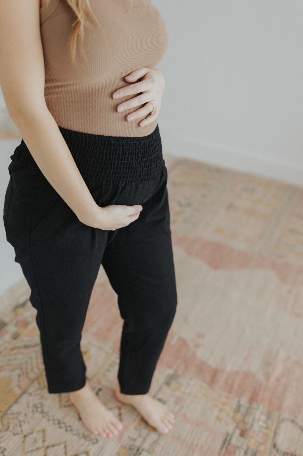 a pregnant woman standing on a rug with her stomach exposed