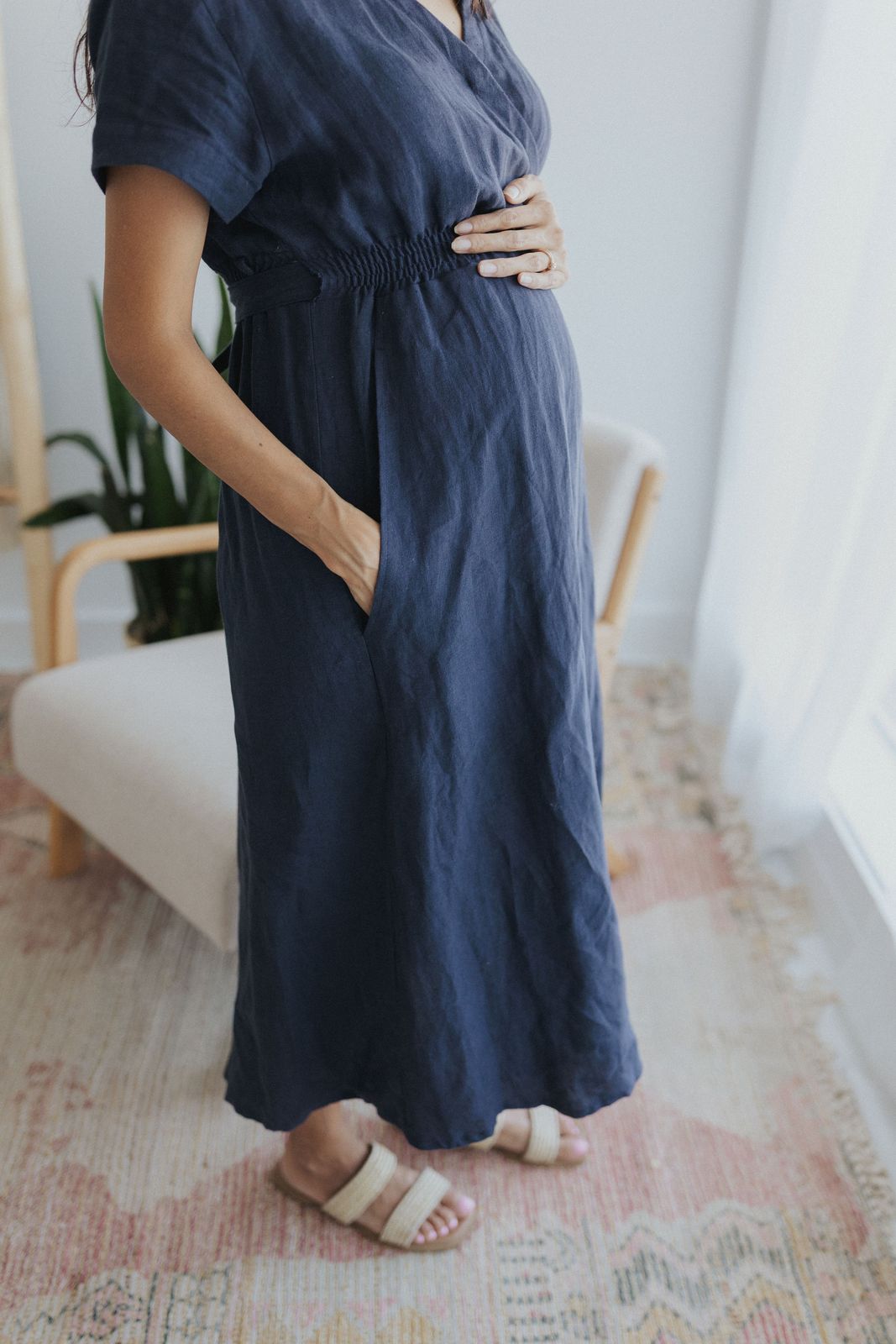 a pregnant woman in a blue dress poses for a picture