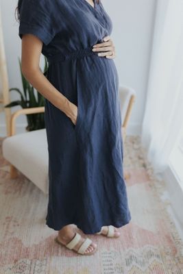 a pregnant woman in a blue dress poses for a picture