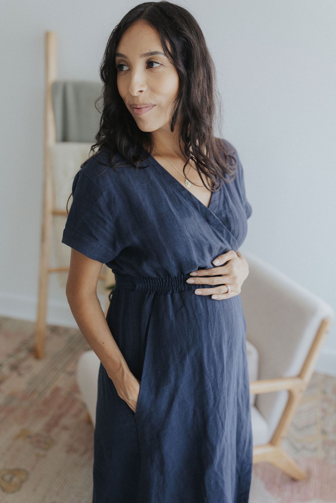 a woman in a blue dress standing in front of a chair