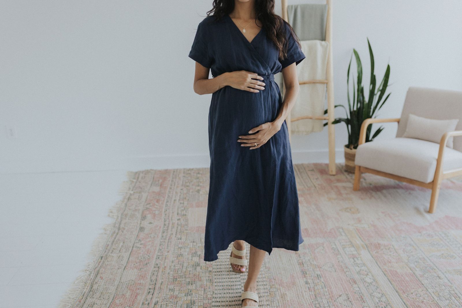 a pregnant woman in a blue dress standing in a room