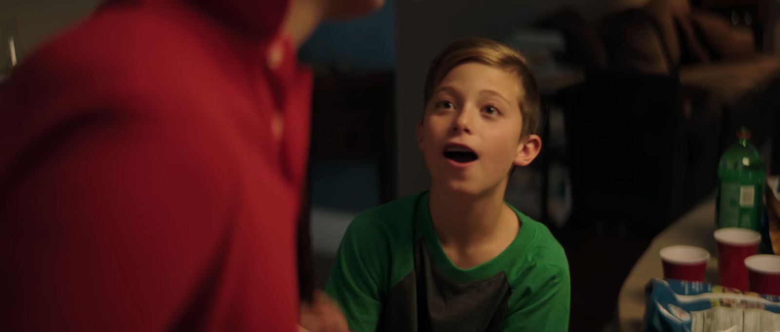 a young boy in a green shirt is making a surprised face