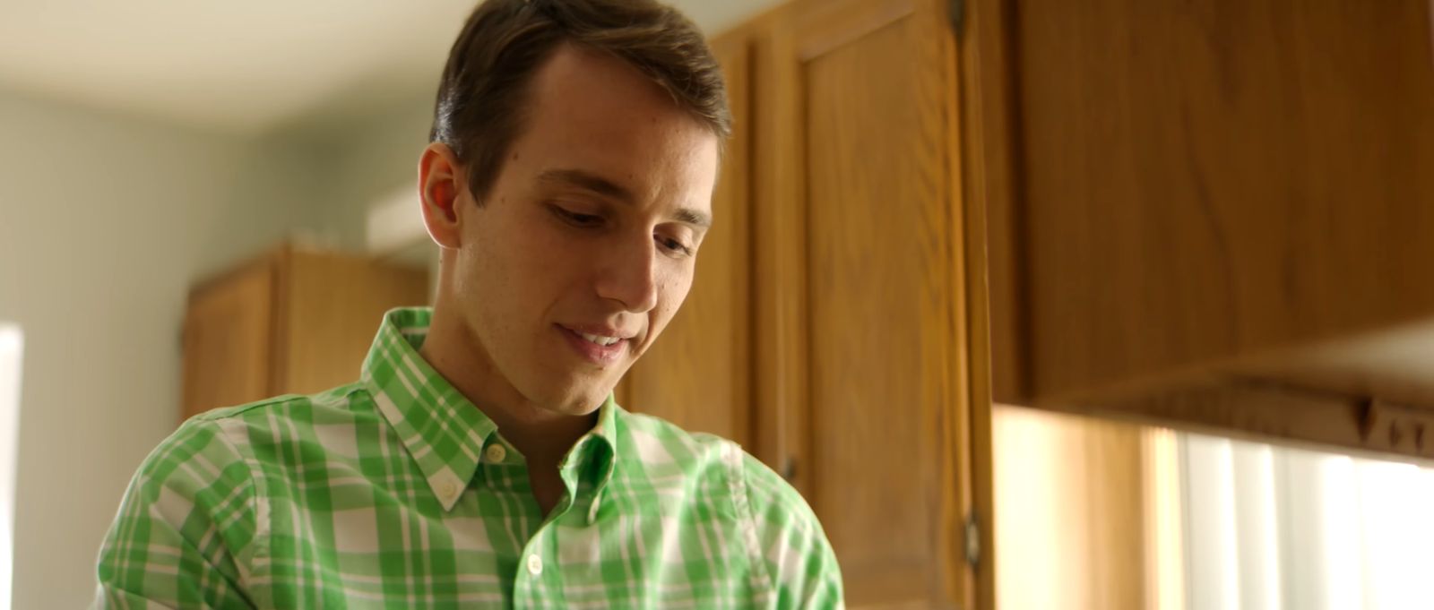 a man in a green and white shirt looking at his cell phone