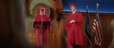 a man in a red graduation gown standing at a podium